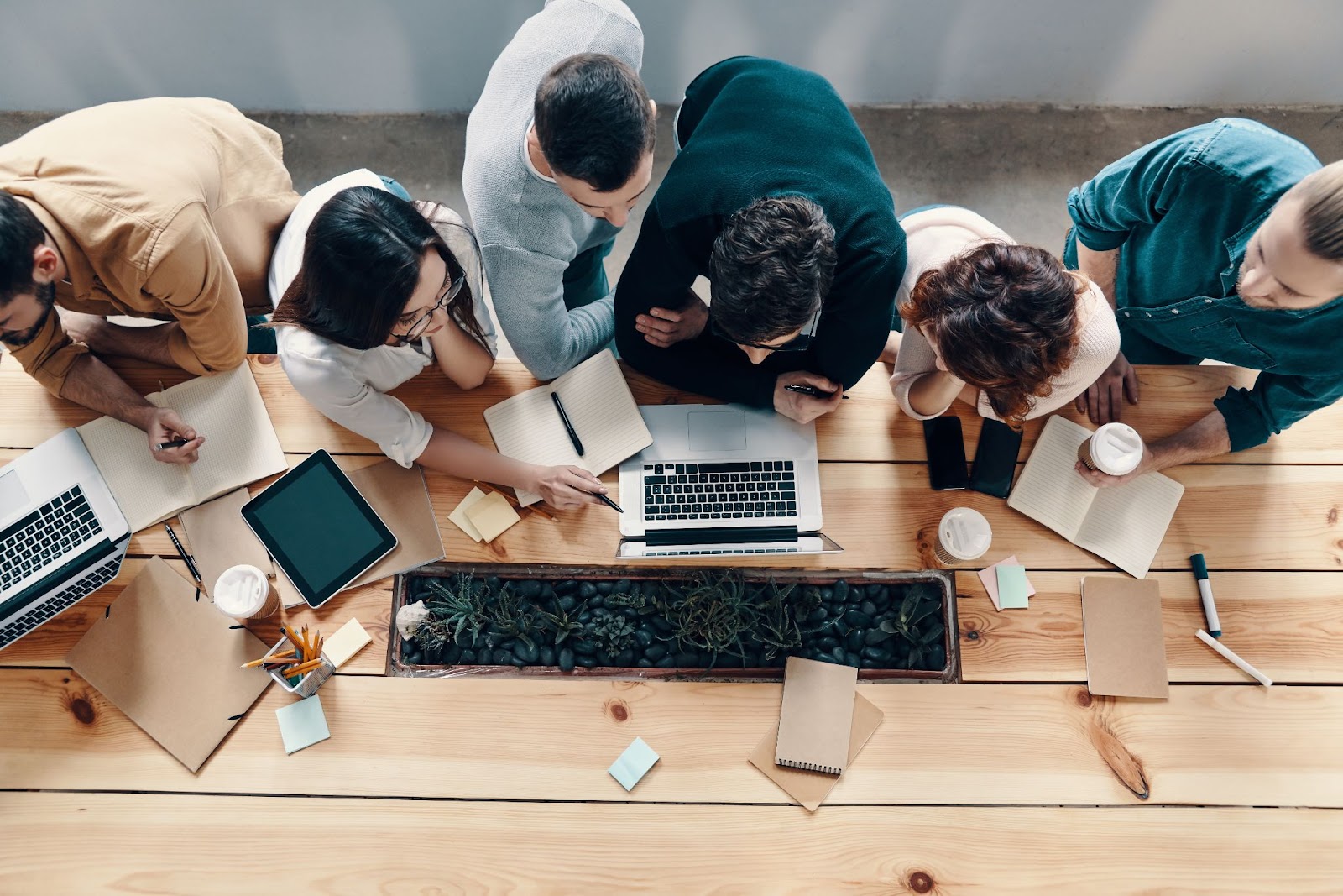 A team collaborating around a table with laptops and notebooks